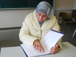 Junge Frau mit Kopftuch beim Punktschriftlesen